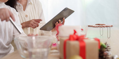 Family preparing Christmas cookies together in a cozy kitchen.の写真素材