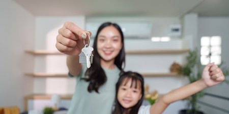 Exciting moment of new home ownership. Mother and daughter celebrating with keys.の写真素材