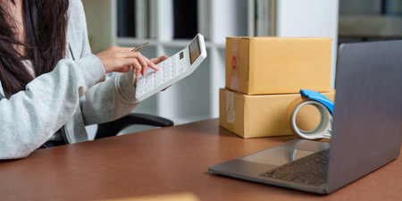 E-commerce: Individual calculating costs while managing packagesの写真素材