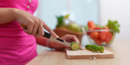 Healthy Meal Prep. Woman cutting cucumber slices for a nutritious dish.の写真素材
