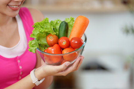 Nutrition Awareness. Woman presenting fresh vegetables in a bowl, highlighting healthy choices.の写真素材