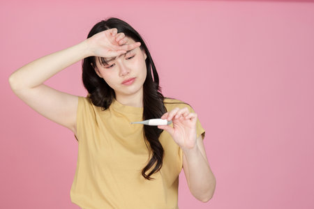 Health Monitoring. Young woman checking temperature with thermometer.の写真素材