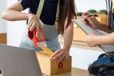Efficient Packaging. Women preparing packages in an e-commerce workspace, showcasing productivity.