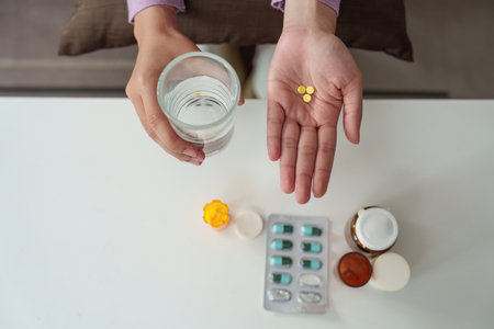 Medication Routine. Individual preparing to take medication with water for health management.の写真素材