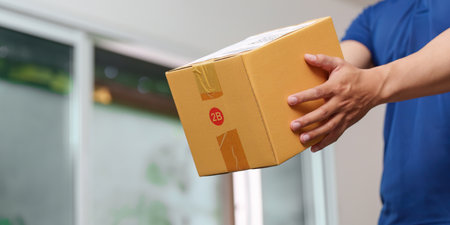 Person handing over a package, showcasing the last step in the shipping process.の写真素材