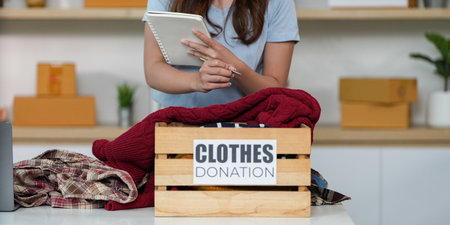 Clothes Donation. Young woman organizing items for charity.の写真素材