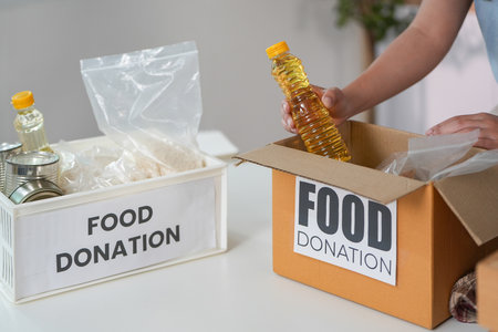 Food Donation. Individual placing cooking oil into donation box.の写真素材