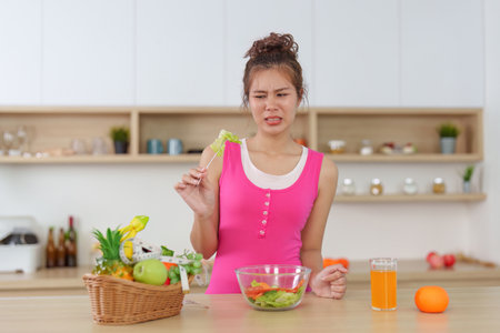 Displeased Eating. Woman reacting to salad in modern kitchen.の写真素材