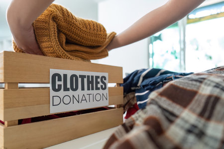 Clothes Donation. Hand placing knitted sweater into donation box.の写真素材