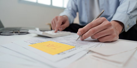 Tax Preparation. Individual calculating taxes with documents and calculator at home office.の写真素材