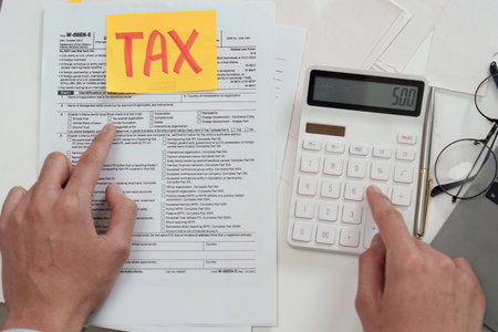 Tax Filing Process. Individual preparing tax forms with calculator and notes.の写真素材