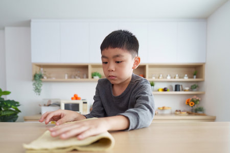 Focused boy learning to clean and organize at homeの写真素材