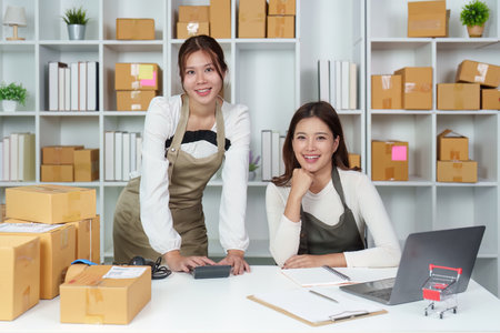 Teamwork in retail. Two women smiling in an e-commerce workspace with packages.の写真素材