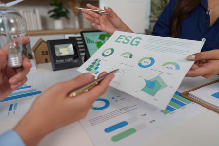 Sustainability and ESG. Professionals discussing environmental strategies with charts and data.の写真素材