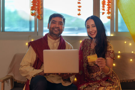 Happy Indian couple using laptop and credit card for online Diwali shopping