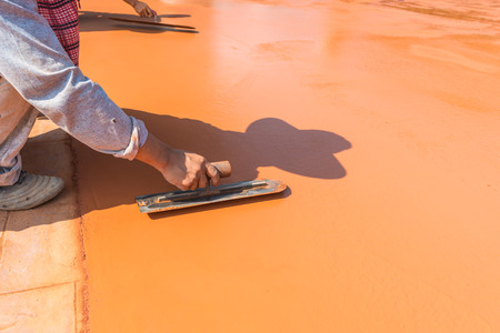 Close-up of hand using trowel to finish wet concrete floorの写真素材