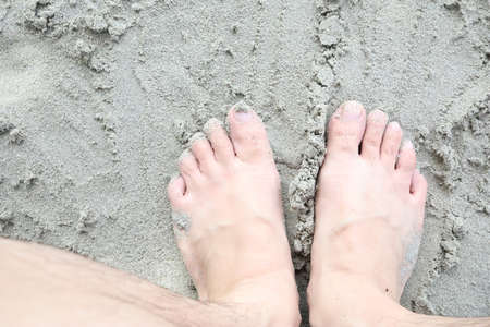 Close-up of a man's feet in the sand on the beach.の写真素材