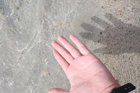 Human hand with shadow on the concrete floor, top view.の写真素材