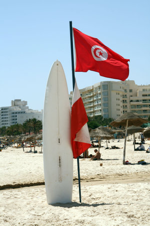 Surfboard with Tunisian flag on the sunny African beach in Sousse