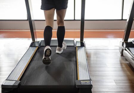 Fitness hall with people running on treadmill next to window with daylight morning exercise health...