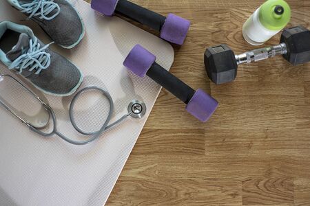 Athlete's set with female clothing, dumbbells , shoesà¸¡ Heart-measuring device,  and bottle of water on blue mat ,wooden floor  background - Imageの写真素材