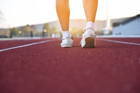Running shoes closeup. Runner on road in track of stadium - closeup of male running walking shoes of jogger outdoors, the evening on sunset - Imageの写真素材
