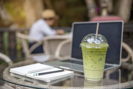Matcha Milk , Milk Green tea latte on glass table  outdoors with beautiful garden backgroundの写真素材