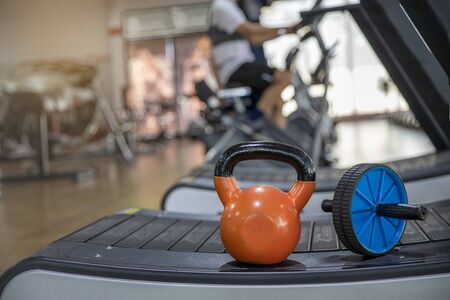 Orange kettlebell and ab roller  on  treadmill in gym. Crossfit kettlebell training in gym. ...