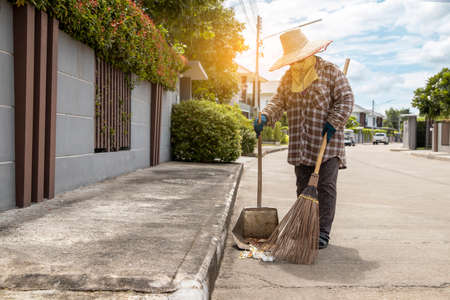 Workers are sweeping the pavement with broom that fall on the street. Street sweeper cleaning roadの写真素材