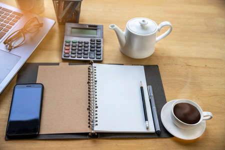 Wood office desk table with smartphone with blank screen, laptop computer, cup of coffee and...