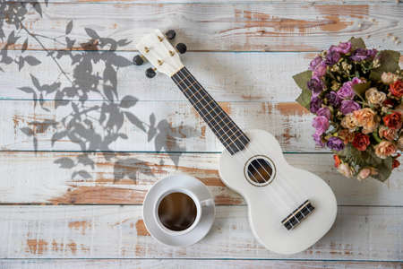 Cup of coffee with ukulele on white wooden background, Vintage styleの写真素材