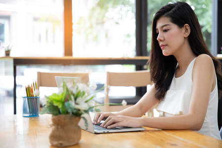 woman using laptop while sitting at cafe. Young  woman sitting in a coffee shop and working on laptop.の写真素材