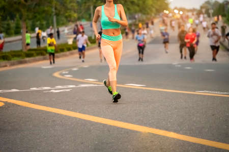 Healthy woman with group of people exercising running , walking on morning park road. workout...