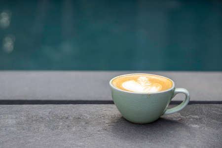 a  cup of hot coffee latte art beside pool. relaxation conceptの写真素材