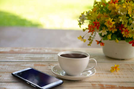 Mobile phone and a cup of coffee on wood texture background, relaxation conceptの写真素材