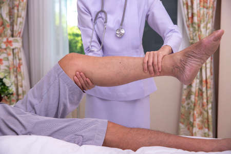 Developing leg muscles. A young nurse doing a leg massage while developing leg muscle of senior man....