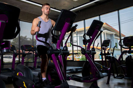 Athlete young man in sportswear doing fitness exercises on xercising on the xtrainer machines  in...