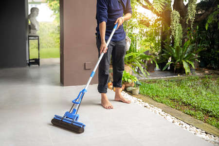 Male janitor with mop cleaning modern house floor. imageの写真素材