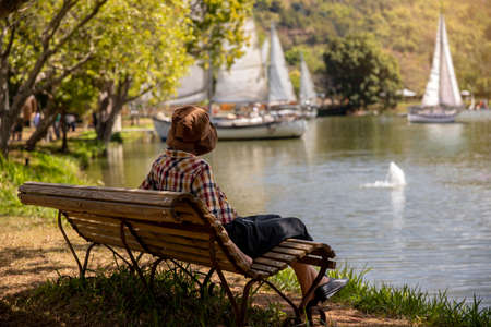 mature woman  sitting on a bench beside a lake on a sunny summer day. holiday concept
