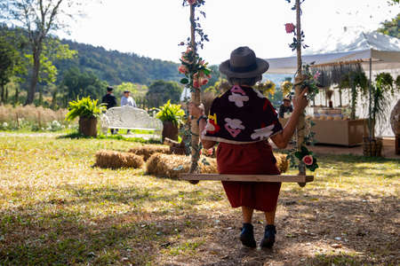 Summer vacation concept, Happy asian woman with hat relax on swing in nature park. holiday concept