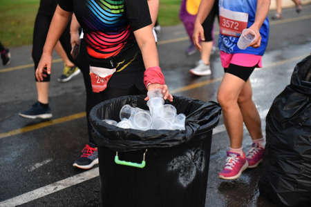 A female athlete throws a plastic cup into a garbage bag. enviroment concept