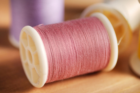 pink thread on wood table shallow depth of field soft focus