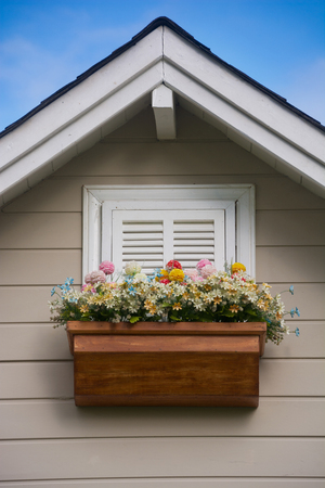 Wooden window with flower at the roof of the house.の写真素材