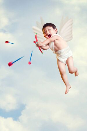 boy cupid with a bow and arrows  fly in the skyの写真素材
