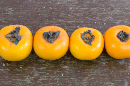 Ripe persimmons on  dark brown wooden background for work decorationの写真素材