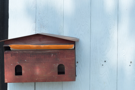 a pale -red mail box hanging on blue wodden background in front of residence or officeの写真素材