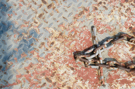 Red rust iron background with chain like cross at a pierの写真素材