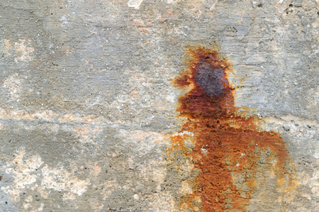 Old concrete wall texture background with dark red burn in the middle caused by rust nail