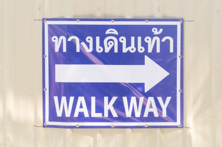 Blue walk way sign with an arrow on it is at subway construction site.