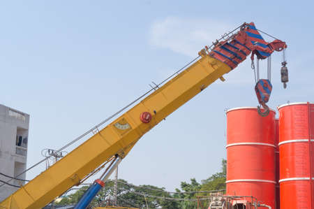 Crane operator and mobile crane machine with red oil tanks at the construction site of subway...